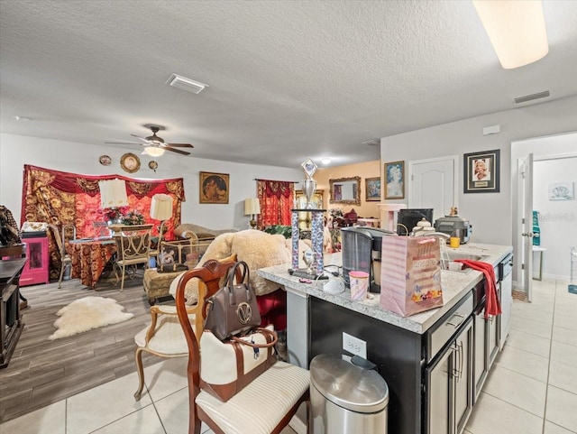 kitchen with visible vents, ceiling fan, a textured ceiling, and open floor plan