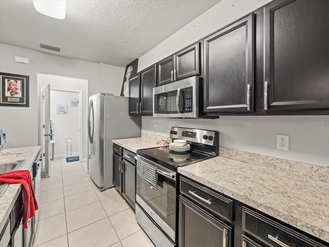 kitchen featuring visible vents, light countertops, light tile patterned floors, stainless steel appliances, and dark cabinets