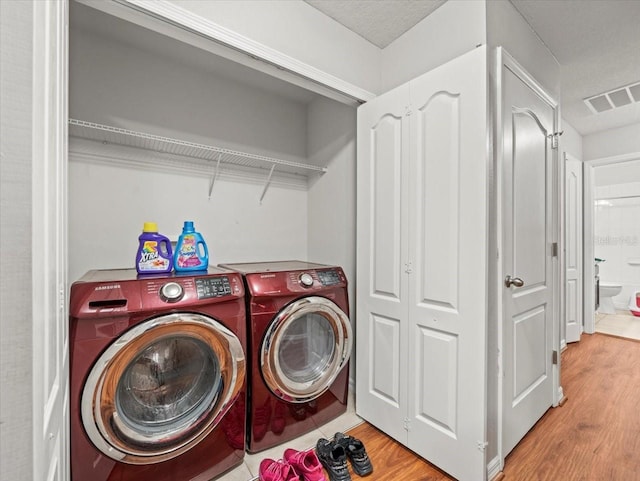 laundry area featuring laundry area, light wood-style floors, visible vents, and washer and clothes dryer