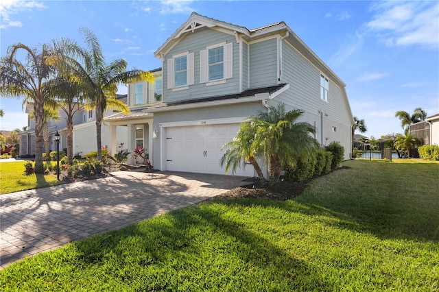 traditional-style home with a front lawn, decorative driveway, and a garage