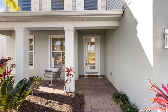 doorway to property with covered porch and stucco siding