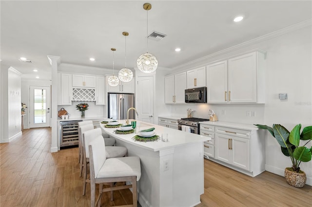 kitchen featuring crown molding, wine cooler, visible vents, and appliances with stainless steel finishes