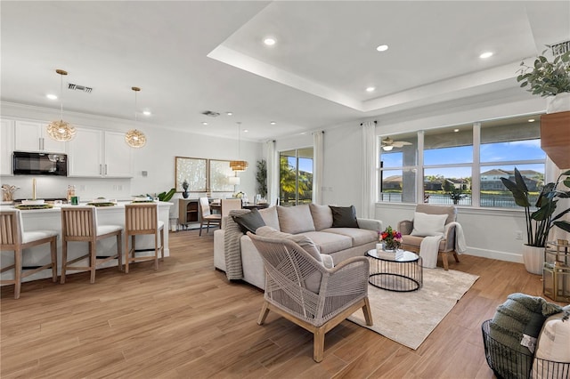 living room featuring light wood finished floors, visible vents, recessed lighting, and a raised ceiling