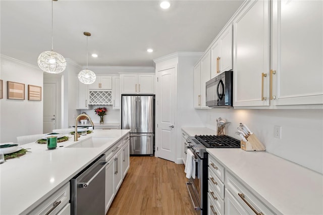 kitchen with light wood finished floors, a sink, light countertops, appliances with stainless steel finishes, and white cabinetry