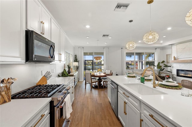 kitchen with a sink, stainless steel appliances, visible vents, and light countertops