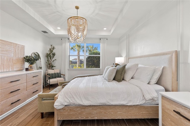 bedroom featuring recessed lighting, a tray ceiling, wood finished floors, and a chandelier