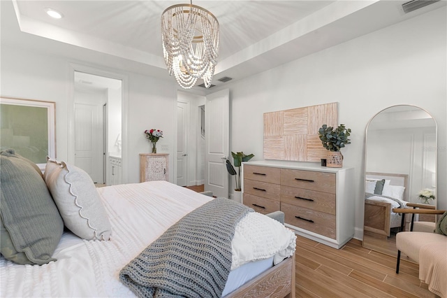 bedroom featuring visible vents, a raised ceiling, a chandelier, and light wood finished floors