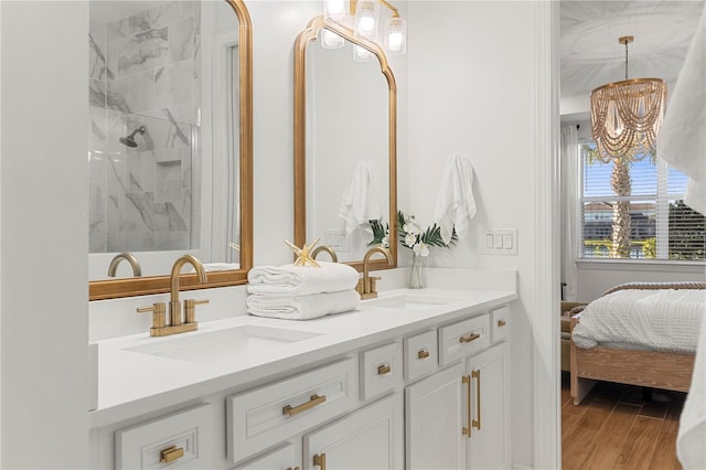 bathroom with double vanity, wood finished floors, a chandelier, and a sink