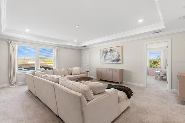 living area featuring a tray ceiling, light carpet, and baseboards