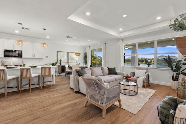 living area featuring recessed lighting, visible vents, light wood-style flooring, and a water view