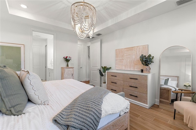 bedroom with visible vents, light wood finished floors, a chandelier, a tray ceiling, and recessed lighting