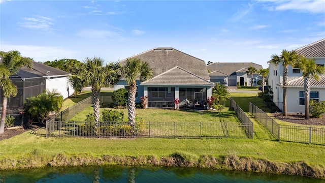 back of property featuring a fenced backyard, a sunroom, a water view, a yard, and a tile roof