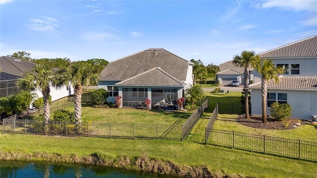 rear view of house with a yard, a water view, a sunroom, and a tile roof