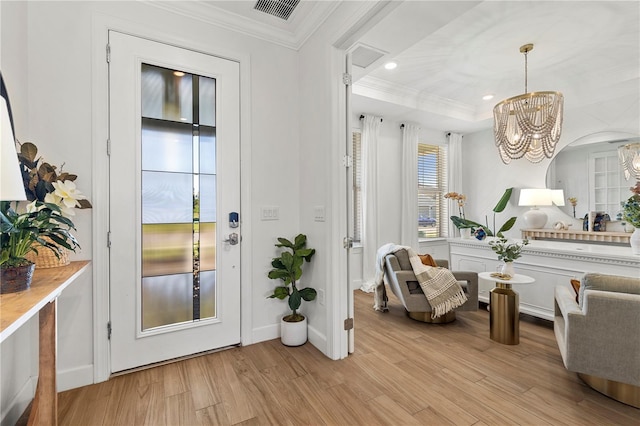 interior space featuring crown molding, light wood-style floors, a chandelier, baseboards, and visible vents