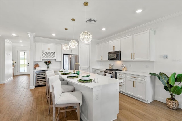 kitchen featuring visible vents, white cabinets, appliances with stainless steel finishes, and wine cooler