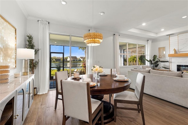 dining area with light wood-style floors, a high end fireplace, a tray ceiling, and recessed lighting