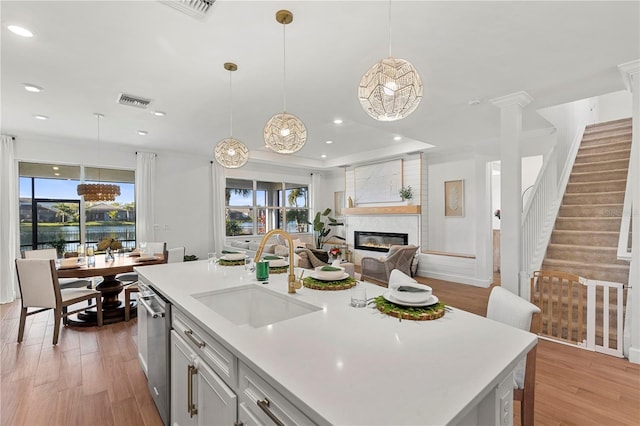 kitchen with a sink, light countertops, open floor plan, and dishwasher