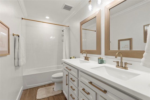 bathroom with a sink, crown molding, wood finished floors, and visible vents