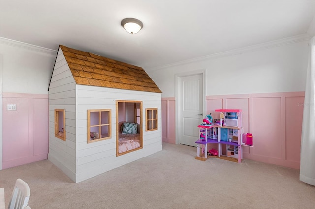 game room featuring carpet floors, ornamental molding, a decorative wall, and a wainscoted wall
