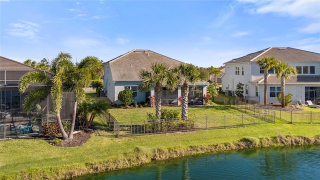 back of property with a water view, stucco siding, and a yard