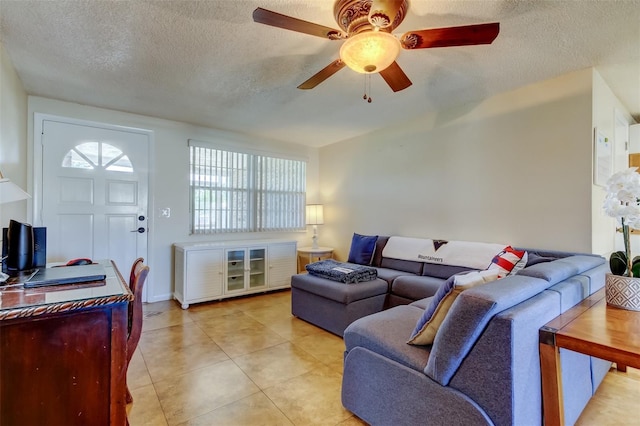 living area featuring a textured ceiling, light tile patterned floors, and ceiling fan