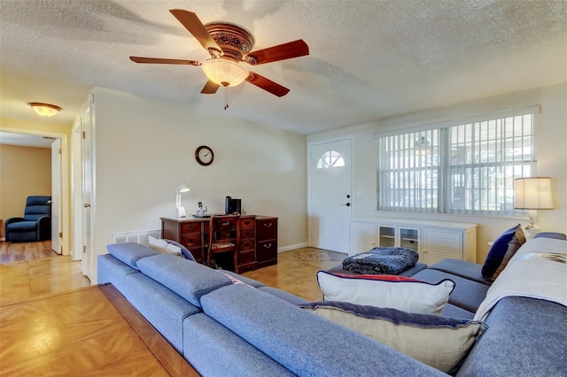 tiled living room with baseboards, visible vents, a textured ceiling, and ceiling fan