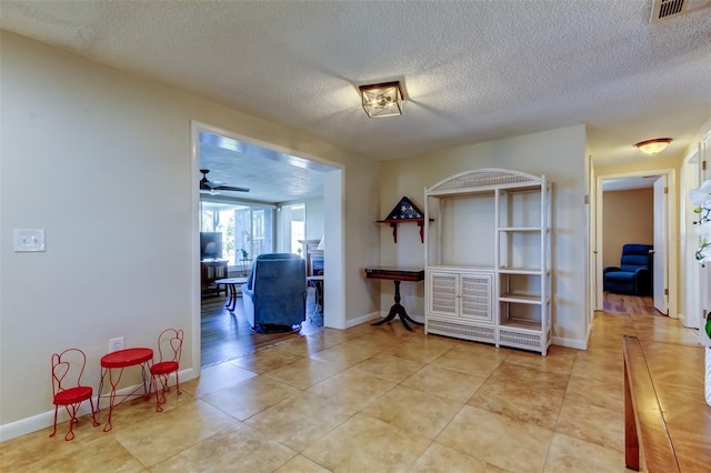 interior space with light tile patterned floors, visible vents, baseboards, and a textured ceiling