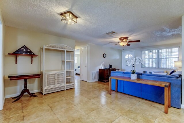 interior space featuring visible vents, baseboards, a textured ceiling, and a ceiling fan