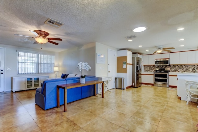 living area featuring a ceiling fan, visible vents, and a textured ceiling