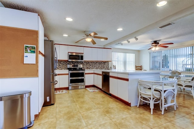 kitchen with visible vents, appliances with stainless steel finishes, a peninsula, and white cabinetry