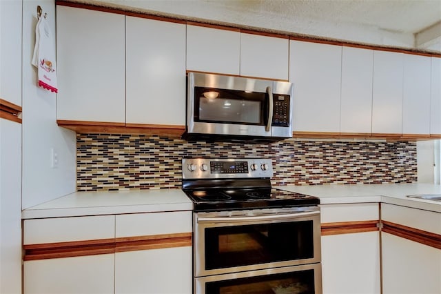 kitchen featuring decorative backsplash, light countertops, white cabinets, and stainless steel appliances