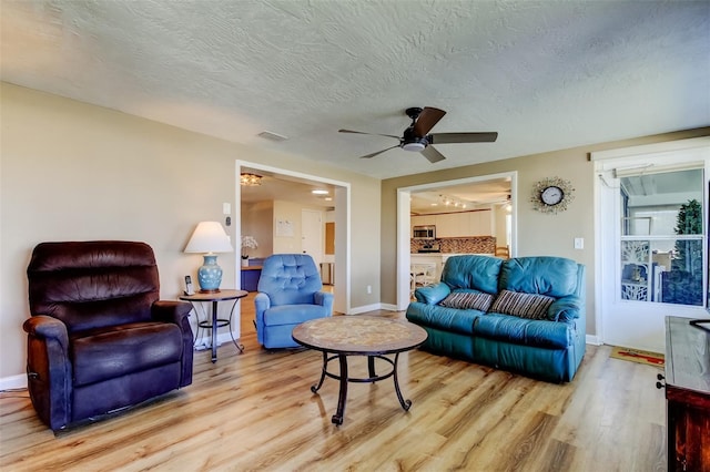 living room with visible vents, a textured ceiling, a ceiling fan, and wood finished floors