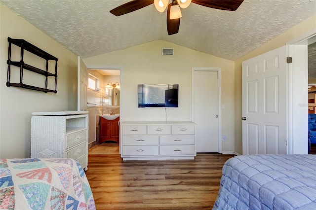 bedroom with visible vents, lofted ceiling, a textured ceiling, and wood finished floors