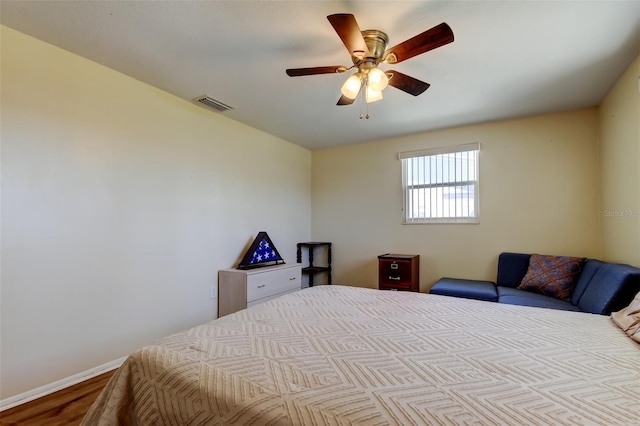 bedroom with visible vents, baseboards, wood finished floors, and a ceiling fan