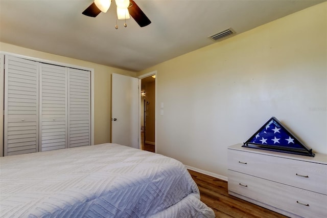 bedroom featuring visible vents, a ceiling fan, wood finished floors, a closet, and baseboards