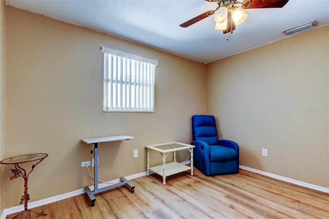 living area with ceiling fan, wood finished floors, visible vents, and baseboards