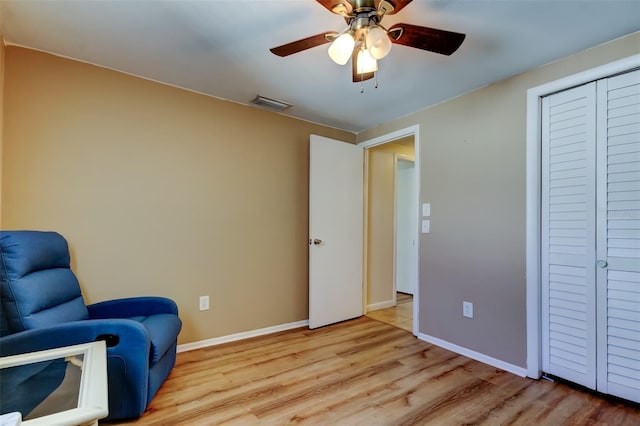 sitting room featuring a ceiling fan, wood finished floors, visible vents, and baseboards