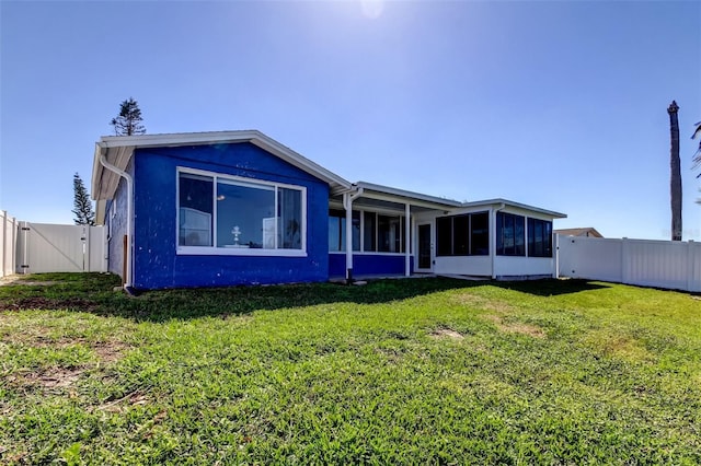 back of house featuring a gate, a lawn, a fenced backyard, and a sunroom