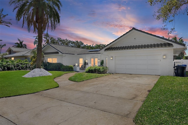 single story home with solar panels, a tiled roof, concrete driveway, a front yard, and a garage