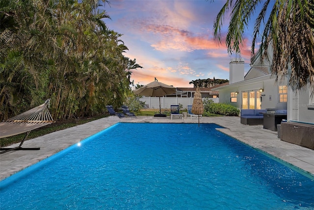 pool at dusk with a fenced in pool, a patio area, and fence