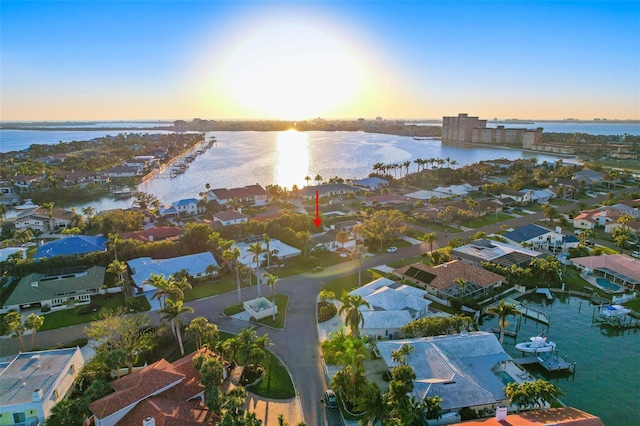 aerial view at dusk featuring a residential view and a water view