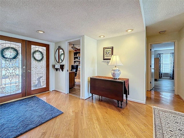 entrance foyer with baseboards, light wood finished floors, recessed lighting, french doors, and a textured ceiling