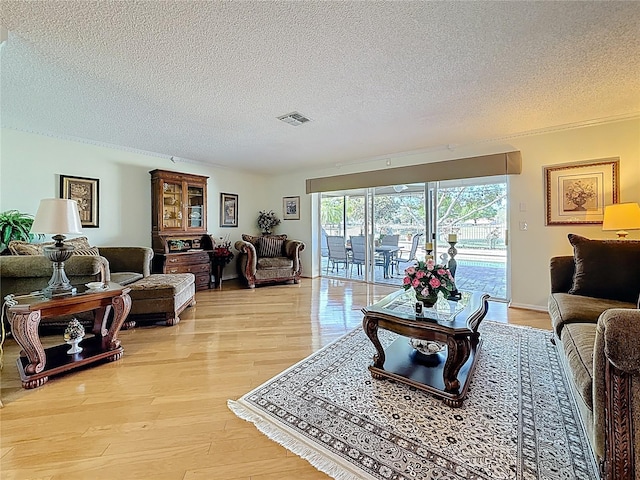 living room featuring visible vents, a textured ceiling, and light wood-type flooring