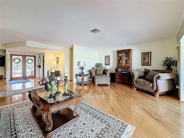 living room with visible vents, french doors, a textured ceiling, and wood-type flooring