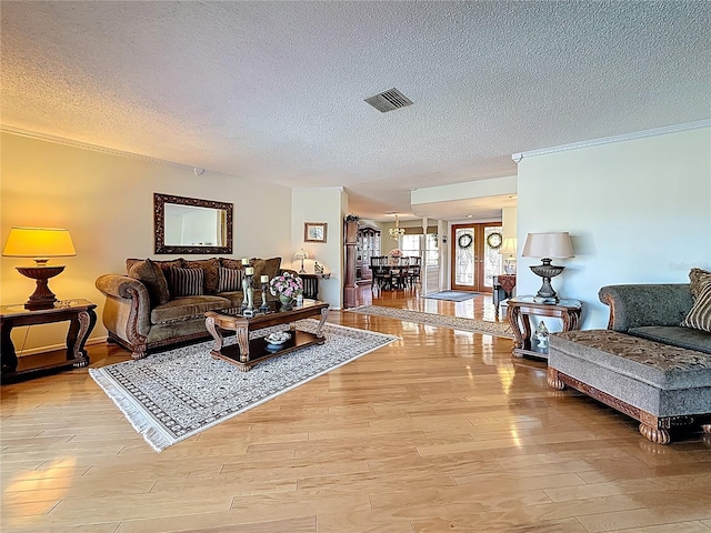 living room with visible vents, crown molding, french doors, wood finished floors, and a textured ceiling