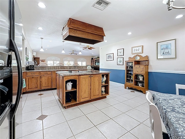 kitchen featuring visible vents, freestanding refrigerator, light tile patterned flooring, brown cabinetry, and open shelves