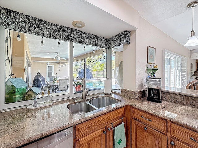 kitchen with stainless steel dishwasher, a healthy amount of sunlight, brown cabinets, and a sink