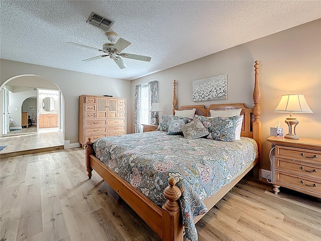 bedroom featuring arched walkways, visible vents, a ceiling fan, and wood finished floors