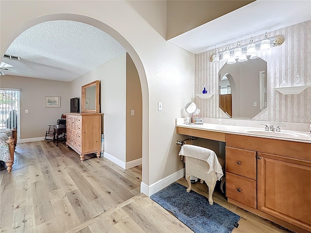 bathroom featuring baseboards, a textured ceiling, wood finished floors, and vanity