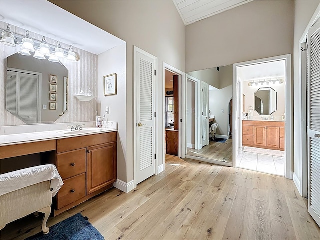 full bathroom with a sink, a closet, two vanities, and wood finished floors